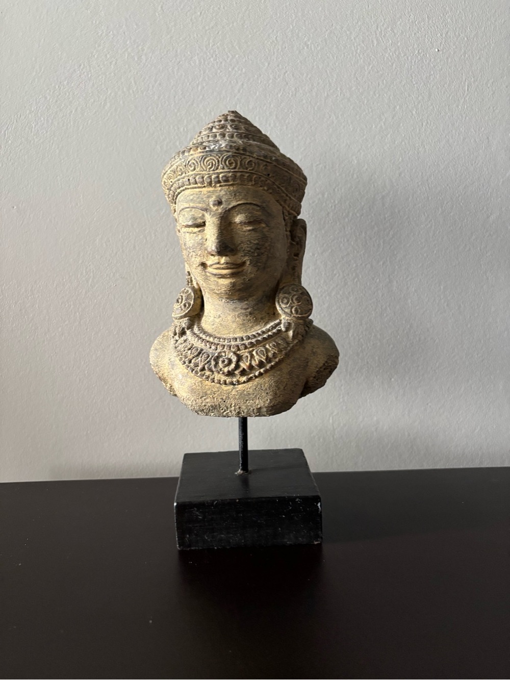 Balinese Buddha head Crafted from stone and displayed on metal and wood stand.